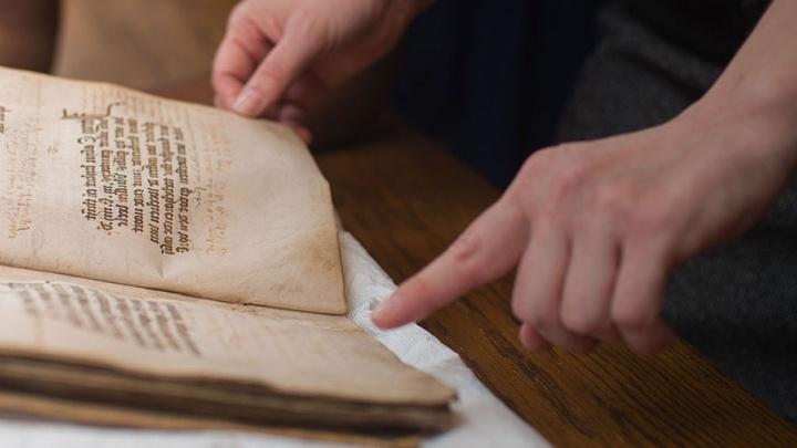 Student h和les age-worn book in the Coates 图书馆 Special Collections 和 Archives.