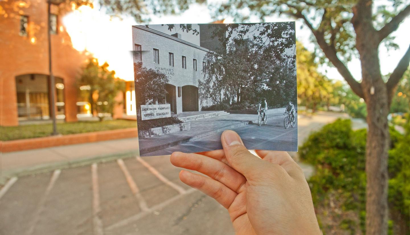 Hand holding a black and white photo of the Chapman building in front of the Chapman building.