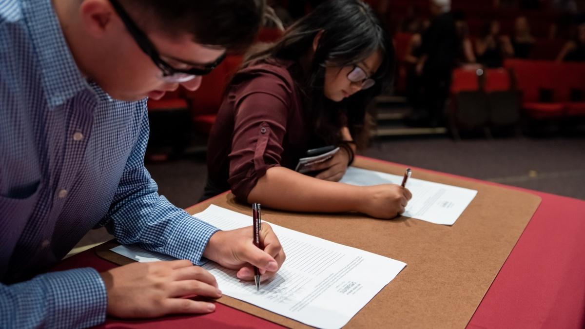 Two students signing the academic honor code