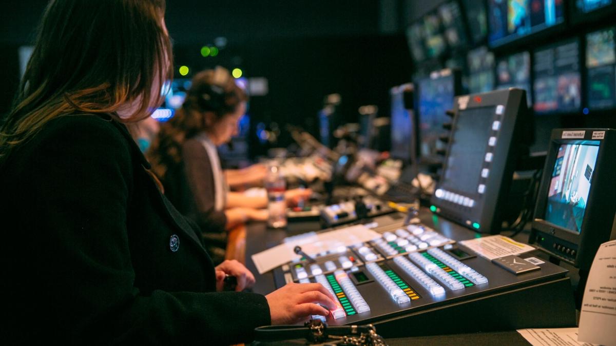 学生 working in a tv control room with control boards and monitors